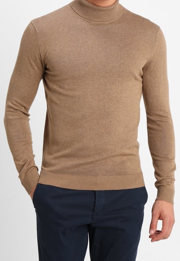 Pull à col roulé marron, léger, au toucher lisse, coupe ajustée avec ourlet et poignets côtelés, porté avec un pantalon bleu marine.
