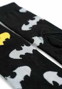 Calzini neri con un motivo di sagome di pipistrelli grigi e gialli, realizzati in tessuto morbido con una texture liscia.