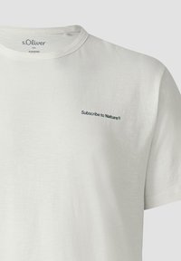 Witte katoenen t-shirt met korte mouwen, met een kleine groene tekst "Subscribe to Nature®" op de borst, ronde hals, zachte textuur.