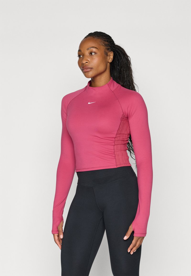 Hosszú ujjú sportpóló rózsaszínben, magas gallérral és texturált oldalsó panelekkel. Magas derekú fekete leggings-szel párosítva.