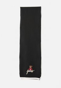 Svart strikket skjerf med et bjørnegrafikk og ordet "guess" brodert i hvitt. Ribbet kant i hvitt og svart. Myk tekstur.