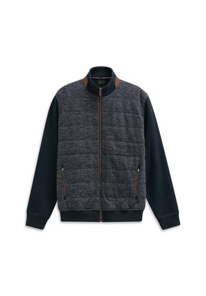 Giacca da uomo con zip, maniche e colletto blu navy, pannello frontale grigio a motivo a zigzag trapuntato, dettagli in suede marrone e tasche con zip.