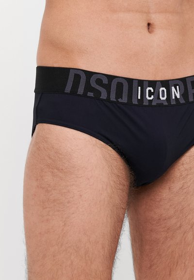 Schwarze Schwimmhose mit einem schwarzen elastischen Bund, der mit dem grauen "DSQUARED2 ICON"-Logo versehen ist. Glattes Material, figurbetontes Design, minimalistischer Stil.
