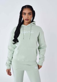 Felpa verde menta con coulisse, tasca a marsupio e logo bianco. Il tessuto sembra morbido e texturizzato; presenta polsini e orlo a costine.