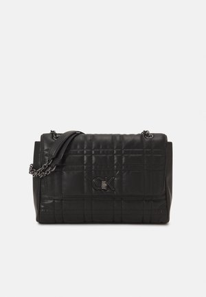 Schwarze gesteppte Leder-Schultertasche mit Kettenriemen und metallischem GK-Logo auf der vorderen Klappe vor einem uni hellen Hintergrund.