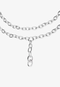 Collier en métal argenté à maillons ovales entrelacés, comportant deux couches et une chaîne plus longue suspendue au centre. Texture lisse.