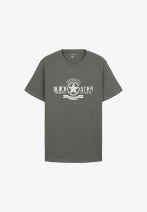 T-shirt in cotone verde oliva con maniche corte, caratterizzato da un design grafico bianco di una stella e la scritta "BLACK STAR" in stile vintage.