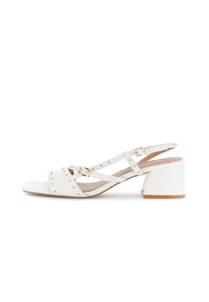 Sandalo bianco da donna con tacco largo, punta aperta, due fibbie dorate e borchie dorate sulle fasce che attraversano il piede e la caviglia.