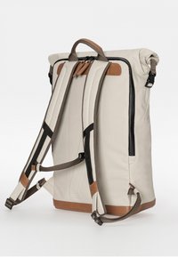 White and tan backpack with padded shoulder straps, top handle, dual zippers, and side pockets; textured fabric with leather accents.