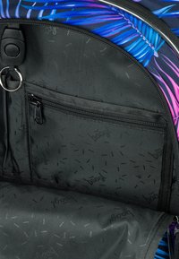 Interno nero di uno zaino con una tasca con zip e un portachiavi. Il materiale presenta un motivo sottile, completato da elementi di design colorati all'esterno.