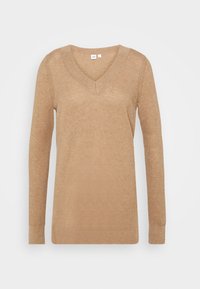 Pull en maille beige avec col en V et manches longues, présentant un motif texturé ainsi que des poignets et un ourlet côtelés.