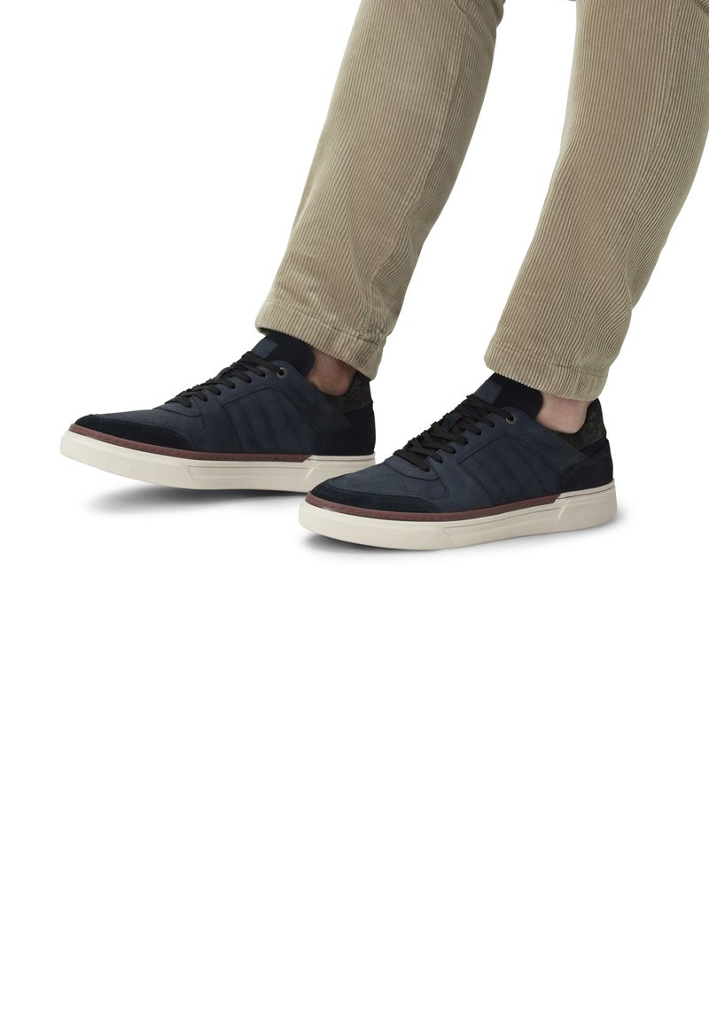 Sneaker blu navy con pannelli in camoscio e rete, suole in gomma bianca e lacci scuri. Accenti testurizzati lungo i lati e design a profilo basso.