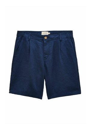 Nærbillede af marineblå fiskebenmønstret bukser med en knappet baglomme og en lyserød skjorte stukket ind.