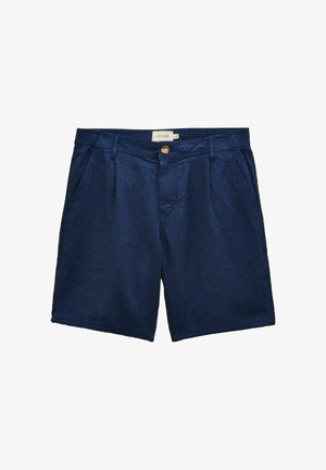 Nahaufnahme von marineblauen Fischgräten-Hosen mit einer geknöpften Gesäßtasche und einem eingesteckten pinken Hemd.