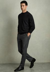 Svart texturerad stickad tröja, grå skräddarsydd byxa och svarta läder dubbla monk strap-skor, med en slim fit-design.