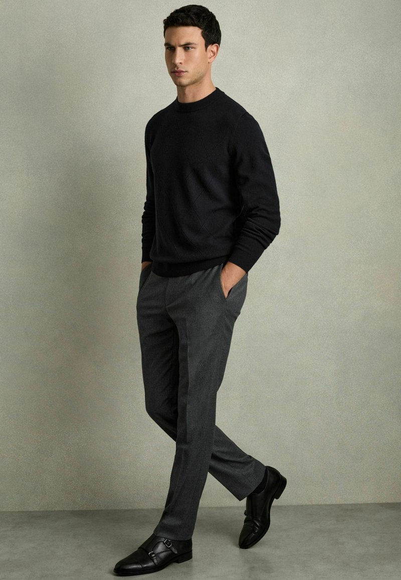 Svart texturerad stickad tröja, grå skräddarsydd byxa och svarta läder dubbla monk strap-skor, med en slim fit-design.