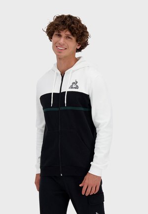 Black and white zip-up hoodie with a green stripe, featuring a hood and front pockets. Logo on chest, made of cotton blend material.