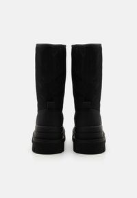Black ankle boots with a smooth finish, featuring a high shaft, solid rubber sole, and minimalistic design. Subtle stitching detail at seams.