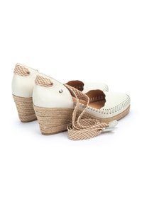 Espadrilles à talon compensé en cuir blanc avec une semelle en jute, des bords en feston et des sangles tressées en marron et beige. Design texturé et léger.