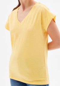 Žluté krátké rukávové tričko s výstřihem do V, vyrobené z měkké bavlny. Nabízí pohodlný střih s minimálními švy na ramenou.