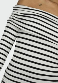 Off-the-shoulder top i sort og hvid strib, med rynkede detaljer. Fremstillet af blødt stof med en tætsiddende silhuet.