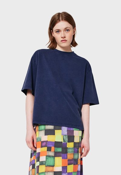 Maglietta oversize blu navy in morbido jersey di cotone con collo rotondo e spalle cadenti, abbinata a una gonna colorata e stampata.