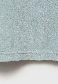 Tessuto in blu chiaro con una superficie morbida e pelosa. L'orlo presenta una finitura pulita e cucita. Focus sulla qualità del tessuto e sui dettagli del colore.