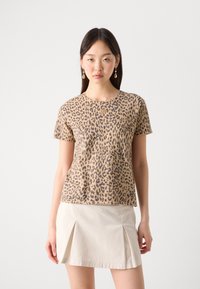 Leopardmønstret t-skjorte med korte ermer i beige og brun. Myk stoff, rund hals og avslappet passform. Kombinert med en lys plisserte skjørt.