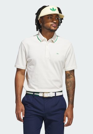 Tricou polo alb cu accente verzi la guler, având un logo brodat. Asortat cu pantaloni navy și o vizieră galbenă cu motiful logo-ului.