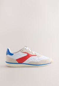 Fehér sportcipő piros és kék részletekkel, texturált dizájnnal, fűzős záródással és puha nubuk bőr ráccsal. Gumi talp tapadómintával.