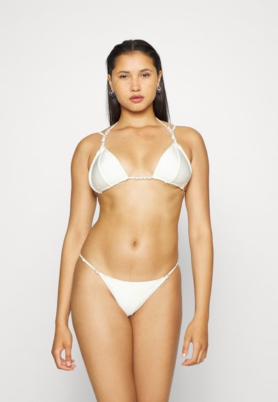 Biquíni branco com um top triangular com detalhes em contas e alças finas; parte de baixo de cintura baixa correspondente com detalhes em contas semelhantes.