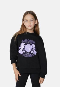 Černá mikina se fialovým grafickým designem "Unicorn Academy" zahrnujícím ozdobné koně a vzor štítu. Měkká tkanina a uvolněný střih, kulatý výstřih.