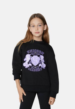 Schwarzer Pullover mit lila "Unicorn Academy" Grafik, die verzierte Pferde und ein Wappen-Design zeigt. Weicher Stoff und lockere Passform, Rundhals-Ausschnitt.