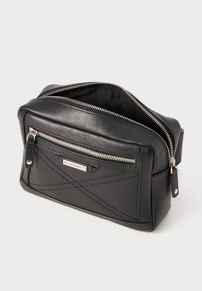 Sac en cuir noir avec un motif matelassé, doté d'une fermeture à glissière sur le dessus et d'une poche zip à l'avant. Accents en métal argenté.