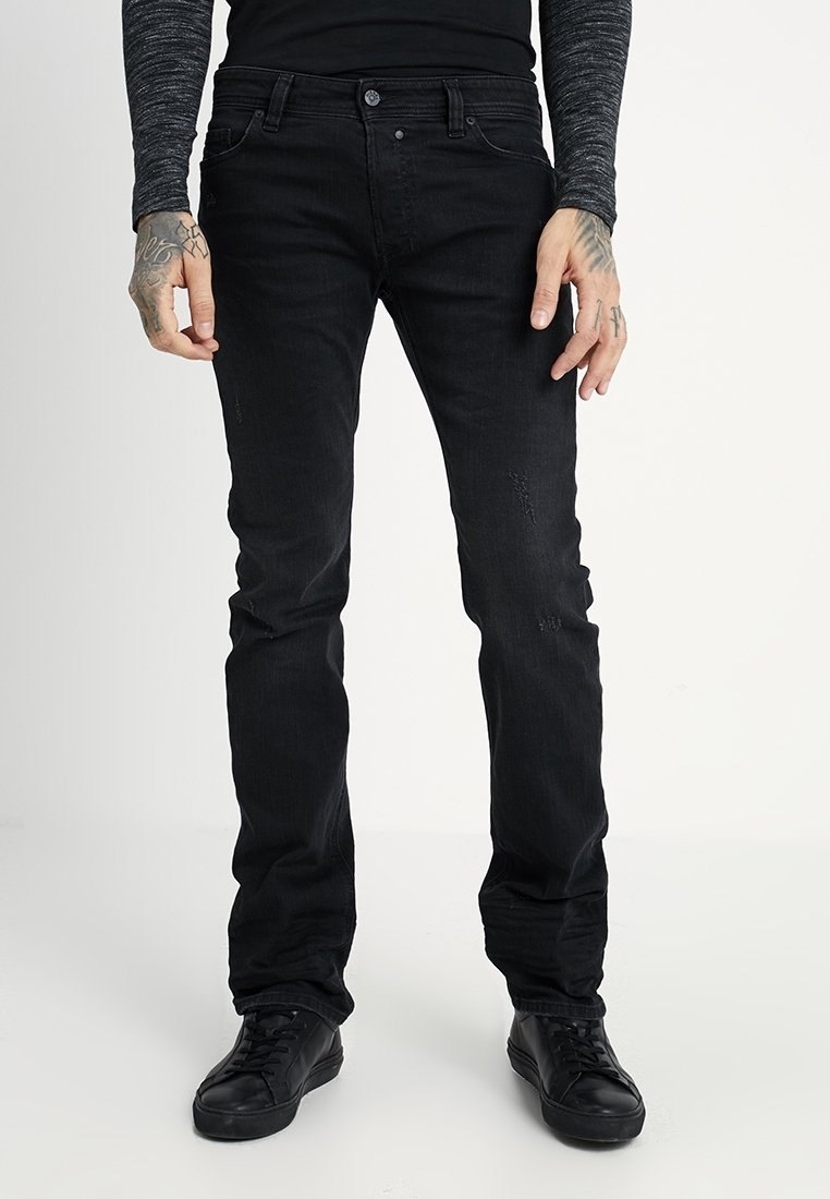 Svarta jeans med slim fit, tillverkade av denim, med lätt slitage och subtila sömnadsdetaljer, paired med svarta sneakers.