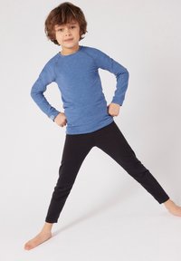 Camicia a maniche lunghe blu con maniche raglan, abbinata a leggings neri. Il tessuto appare morbido con una leggera elasticità, adatta per abbigliamento attivo.