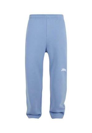 Light blue sweatpants with an elastic waistband, tapered legs, and a white logo on the left thigh. Made from soft, textured fabric.