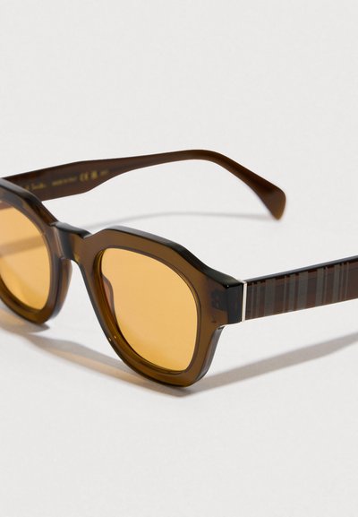 Gafas de sol marrones con montura redondeada, lentes tintadas de color amarillo y varillas con rayas y acentos marrones. Detalle delgado de metal en la bisagra.