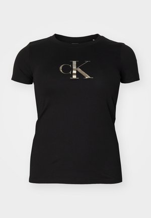 Musta lyhythihainen t-paita, jossa metallinhohtoinen hopeanvärinen "cK"-logo keskellä rintaa, yksinkertainen pyöreä kaula-aukko.