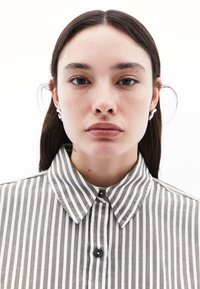 Camicia a righe grigia e bianca in tonalità tenui, con colletto classico e motivo a spina di pesce. Tessuto liscio con una leggera lucentezza.