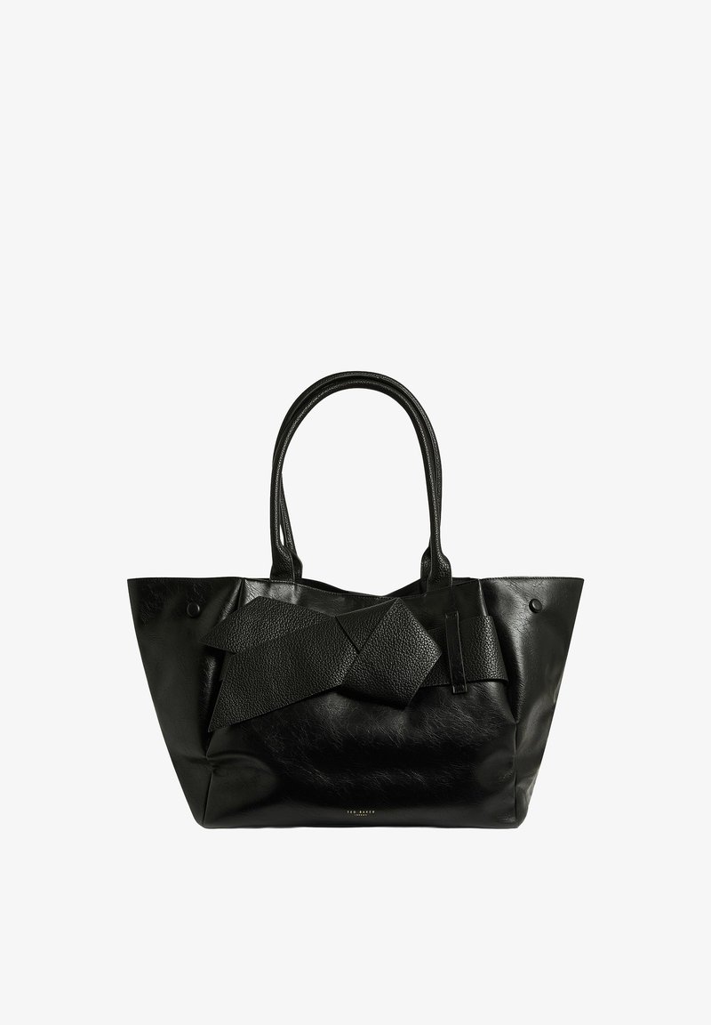 Sac cabas en cuir noir avec un grand nœud texturé sur le devant et deux poignées doubles.