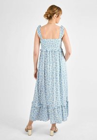 Rochie maxi dintr-un material albastru deschis cu modele florale. Prezintă bretele cu volane și un corset strâns, având o margine în straturi.