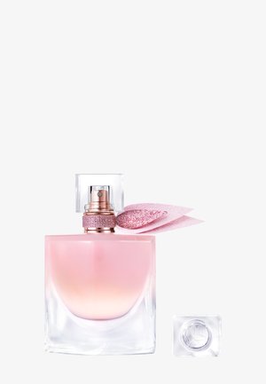 Flacon de parfum en verre clair avec une base dégradée rose, mettant en avant un bandeau pailleté doré et rose ainsi qu'un bouchon carré translucide, à côté d'un petit bouchon carré.
