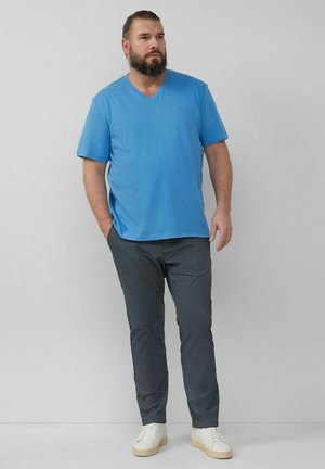 Blue cotton V-neck t-shirt paired with gray trousers, featuring a relaxed fit and smooth texture. Footwear consists of white sneakers.