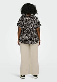 Halenka s leopardím vzorem s krátkým rukávem a detaily na zadní straně, kombinovaná s krémovými širokými kalhotami a černými teniskami.