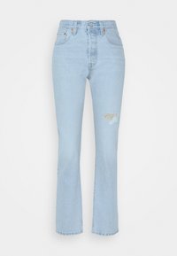 Jeans de tiro alto en azul claro con pierna recta, que presentan un parche rasgado en la rodilla y un sutil detalle de costura. Material de mezclilla clásico.