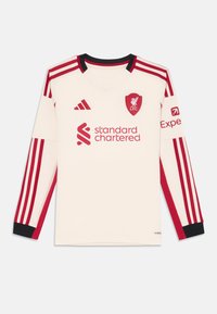 Duguljasta Liverpool FC majica tamnosmeđe boje s crvenim prugama, s v-izrezom, klupskim logotipom i logotipom sponzora na prednjoj strani. Crni akcenti na rukavima.