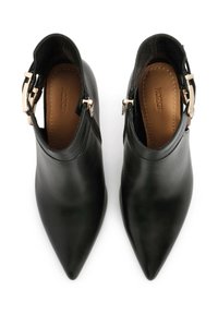 Botines de cuero negro hasta el tobillo con punta afilada, que presentan un diseño recortado y un acento de hebilla dorada en el lateral. Textura suave en toda la superficie.
