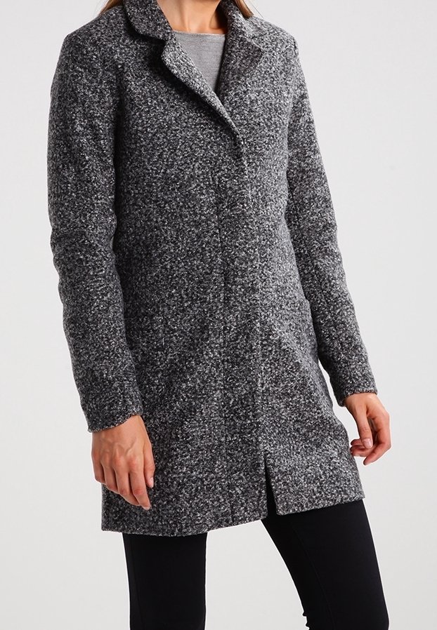 Femme portant un manteau en laine grise texturée mi-long, à manches longues, col à revers et fermeture avant dissimulée, assorti à un pantalon noir.