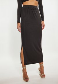 Zwarte geribbelde midi-rok met zijwaartse split, elastische tailleband, gecombineerd met gouden gespsandalen met hoge hakken. Glad textuur, aansluitend ontwerp.